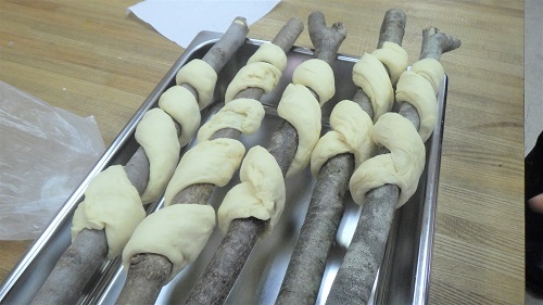 パン生地を枝に巻き付けた画像