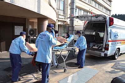 入院患者役の人を搬送する鹿島病院の職員と救急隊員（訓練）の画像