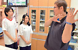 施設の職員（右）から仕事の説明を受ける生徒の写真