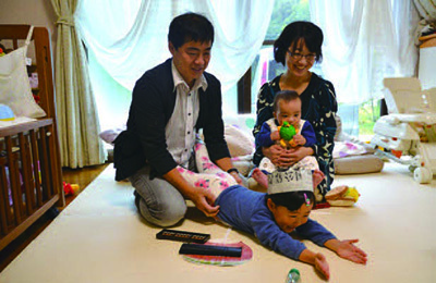 居間で家族とくつろぐ金弦勇さんと敬子さんの写真