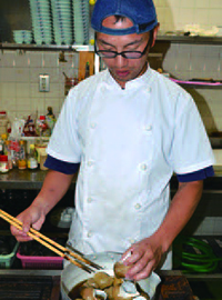 白バイ貝の煮付けを作る池田彰邦さんの写真