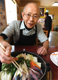 鍋にサバを盛り付ける次藤昇之輔さんの写真