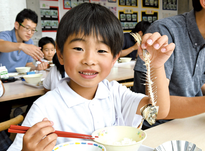 給食のマアジをきれいに食べる三隅小の1年生の写真