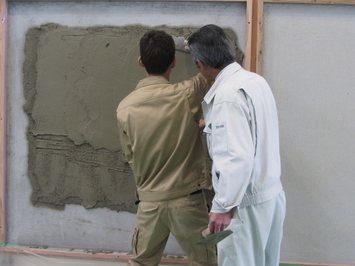 壁に泥を塗りつけています