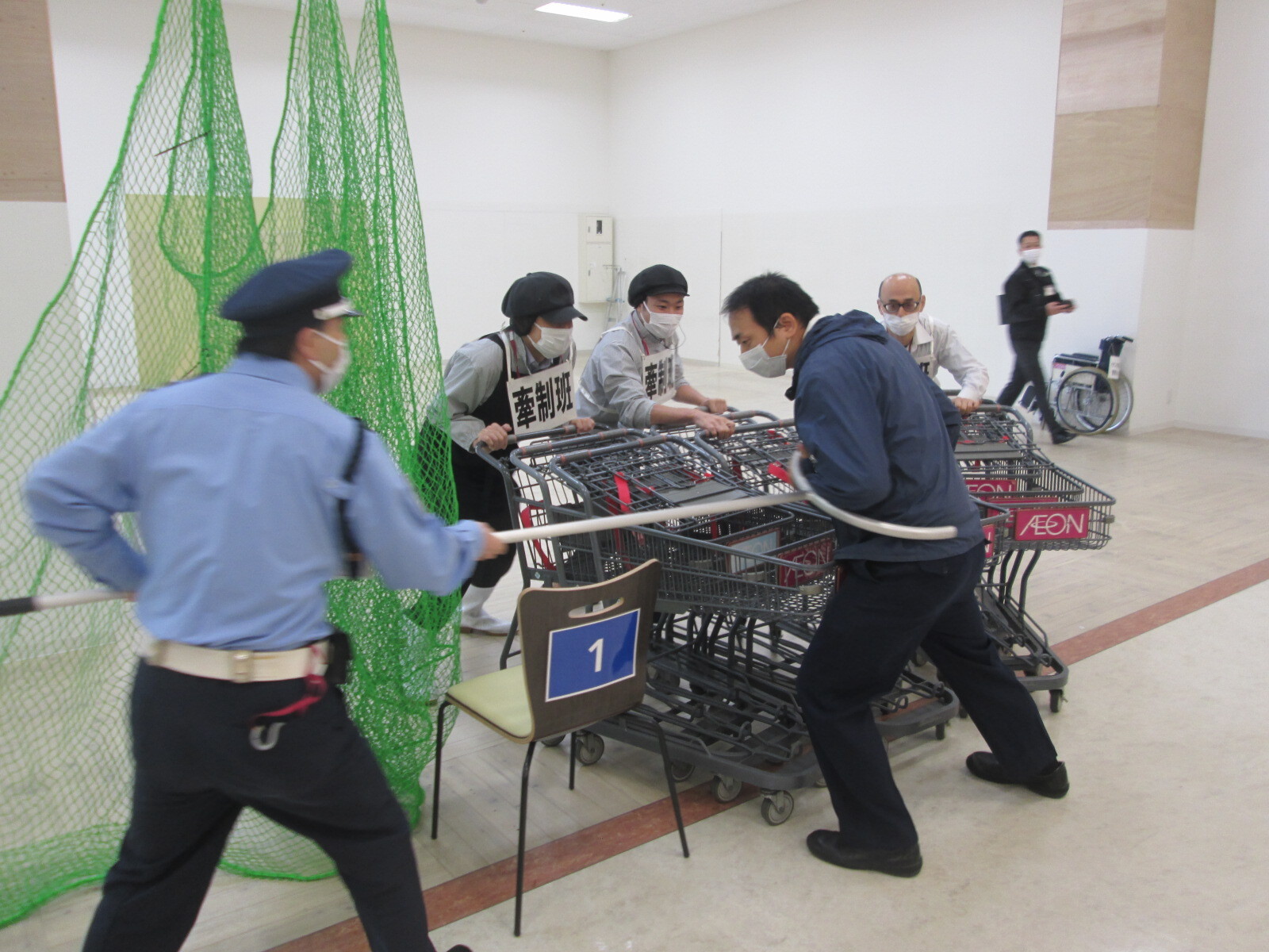 大型買物カートと刺股を用いて不審者と間合いをとっている写真